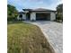 Single-story home with attached garage and gray paver driveway at 124 Hercules Dr, Rotonda West, FL 33947