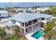 Aerial view of coastal estate with a metal roof, a backyard pool, and an outdoor living area overlooking the water at 10009 Gasparilla Pass Blvd, Boca Grande, FL 33921