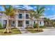 Elegant two-story home featuring a charming front porch, wooden accents, and lush landscaping with mature palm trees at 10009 Gasparilla Pass Blvd, Boca Grande, FL 33921