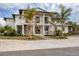 Stunning two-story home with a spacious front porch, wooden details, complemented by verdant palm trees and a stone driveway at 10009 Gasparilla Pass Blvd, Boca Grande, FL 33921