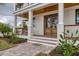 Inviting front porch with wooden columns, a cozy seating area, and a charming entrance with double doors at 10009 Gasparilla Pass Blvd, Boca Grande, FL 33921