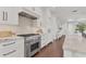 Modern kitchen with stainless steel stove, stylish backsplash, white cabinets, and hardwood floors, perfect for cooking at 10009 Gasparilla Pass Blvd, Boca Grande, FL 33921