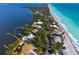 Breathtaking aerial shot of a beachfront property with lush surroundings, a private dock, and crystal-clear turquoise waters at 6895 Manasota Key Rd, Englewood, FL 34223