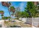 Beautiful beachfront backyard, featuring white picket fence, lush landscaping, and picturesque palm trees at 6895 Manasota Key Rd, Englewood, FL 34223