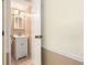 A tidy half-bathroom featuring a vanity with storage and a well-lit mirror is located next to the garage at 6895 Manasota Key Rd, Englewood, FL 34223
