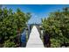 Wooden dock with pilings extending into the bay, framed by lush greenery at 6895 Manasota Key Rd, Englewood, FL 34223