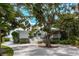 Inviting two-story home featuring lush landscaping, white exterior, and grand oak tree at 6895 Manasota Key Rd, Englewood, FL 34223
