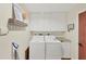Well-lit laundry room with washer, dryer, and overhead cabinets at 7192 N Paragon Rd, North Port, FL 34291