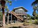 Elevated beach house with a large deck and surrounding palm trees at 8934 Gulf St, Placida, FL 33946