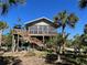 Stilted beach home with wrap-around porch and tropical landscaping at 8934 Gulf St, Placida, FL 33946