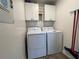 Bright laundry room with washer, dryer, and overhead cabinets at 8934 Gulf St, Placida, FL 33946