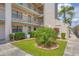 Condo with beautiful landscaping, including green grass, bushes, and a palm tree at 175 Kings Hwy # 1014, Punta Gorda, FL 33983