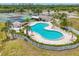 Aerial view of a pool with lounge chairs and shade, tennis courts, and green landscaping at 175 Kings Hwy # 1014, Punta Gorda, FL 33983