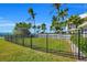 Spacious backyard with a lush lawn, palm trees, and a black metal fence at 12440 Placida Rd, Placida, FL 33946