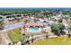 An aerial view features the community pool and clubhouse with a beautiful pond and a scenic tree line at 13525 Dibella Ave, Port Charlotte, FL 33981