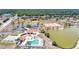 An aerial view showcases the community clubhouse, pool, tennis, shuffleboard courts, and scenic pond at 13525 Dibella Ave, Port Charlotte, FL 33981