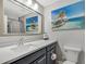 Light and airy bathroom with a large mirror and a beach themed painting at 13525 Dibella Ave, Port Charlotte, FL 33981
