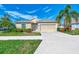 Single-story home with attached garage, landscaping, and palm trees at 584 Gadsen St, Englewood, FL 34223