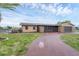 Single story home with stone accents, a circular driveway and a well maintained lawn at 76 Caddy Rd, Rotonda West, FL 33947