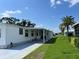 White mobile home with covered patio and lawn at 8485 Nighthawk Dr, Englewood, FL 34224