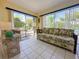 Sunroom with tiled floors, floral couch, and sliding glass doors at 13468 Romford Ave, Port Charlotte, FL 33981