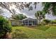 Spacious backyard with screened-in patio area and tropical plants at 110 S Oxford Dr, Englewood, FL 34223