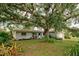 Light blue ranch home with lush landscaping and large oak tree at 110 S Oxford Dr, Englewood, FL 34223