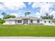 White one-story home with brown accents, screened porch, and landscaped lawn at 5039 Parker St, Port Charlotte, FL 33981