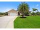 Tan one-story house with a two-car garage and lush lawn at 15889 Viscount Cir, Port Charlotte, FL 33981