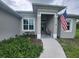 Front porch of a gray house with American flag and landscaping at 48 Long Meadow Ln, Rotonda West, FL 33947