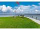 Serene waterfront view with American flag, lush grass, and tranquil waters at 13074 Via Flavia, Placida, FL 33946