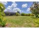 Large backyard with grassy area, tropical plants, and home view at 639 Boundary Blvd, Rotonda West, FL 33947