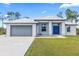 Single-story home with gray metal roof, blue door, and attached garage at 9239 Harvester St, Port Charlotte, FL 33981