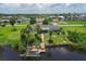 Aerial view showcasing a waterfront home with a private dock, lush landscaping, and surrounding residential area at 2516 Dixon Ter, Port Charlotte, FL 33981