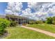 Landscaped backyard with a screened-in porch, lush green grass, and a brick pathway to the home at 2516 Dixon Ter, Port Charlotte, FL 33981