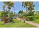 Beautifully landscaped backyard with a brick path, lush greenery, palm trees, and a wooden dock at 2516 Dixon Ter, Port Charlotte, FL 33981