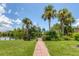 The backyard features lush green grass, a brick pathway leading to a wooden dock, and beautiful landscaping at 2516 Dixon Ter, Port Charlotte, FL 33981