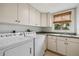 Bright laundry room, features washer, dryer, cabinets, and window at 13310 Anglers Way, Placida, FL 33946
