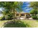 Back exterior of the house showcasing a large tree and patio at 1867 Neptune Dr, Englewood, FL 34223