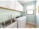 A laundry room with a stainless steel sink, a window and white washer and dryer at 1012 Bradberry Dr, Nokomis, FL 34275