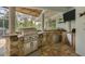 Covered outdoor kitchen with a built-in grill, a stone countertop, and a bar area for entertaining guests at 200 Capstan Dr, Placida, FL 33946