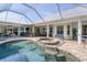 Inviting backyard pool and spa area with a screened enclosure, an outdoor kitchen, and ample seating at 200 Capstan Dr, Placida, FL 33946