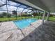 Covered outdoor pool area with travertine tile, screened enclosure and open backyard at 261 Broadmoor Ln, Rotonda West, FL 33947