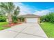 Front view of a single-Gathering home with a white garage door and palm trees at 14143 Saul Ln, Port Charlotte, FL 33981