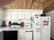White kitchen with wood ceiling, microwave, refrigerator and stove at 208 Marlette Dr, North Port, FL 34287