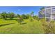 Spacious backyard with grassy area, tropical plants, and a screened pool enclosure at 283 Long Meadow Ln, Rotonda West, FL 33947