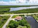 Waterfront property with a private dock and boat lift, surrounded by lush greenery and a nearby roadway at 15964 Viscount Cir, Port Charlotte, FL 33981