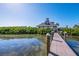 Wooden community dock leading to a house with lush green plants and waterfront views at 6000 Boca Grande Cswy # D46, Boca Grande, FL 33921