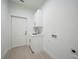 An empty laundry room with light tile flooring, a utility sink, and a door leading to the outside at 9262 Genesee St, Port Charlotte, FL 33981