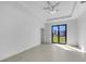 Minimalist bedroom with tray ceiling, ceiling fan, large windows, and tile floor at 9262 Genesee St, Port Charlotte, FL 33981
